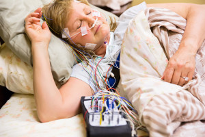 Woman sleeping in a bed in the hospital with equipment attached during a sleep study. 